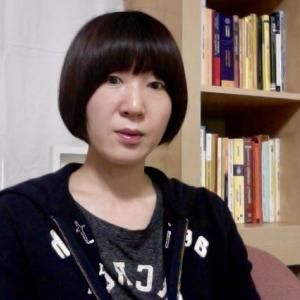 Dr. Hee Jung Kim stands near a bookshelf