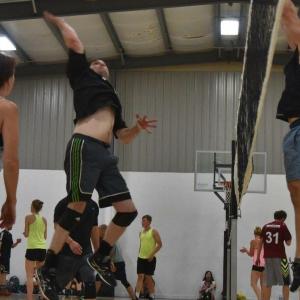 Stephen in a midair pose while playing volleyball in a gym 