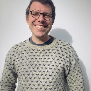 Wearing a sweater and glasses in front of a white background